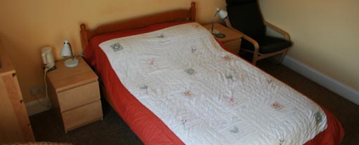 An image of a clean and tidy bedroom containing a single bed and two bedside cabinets.