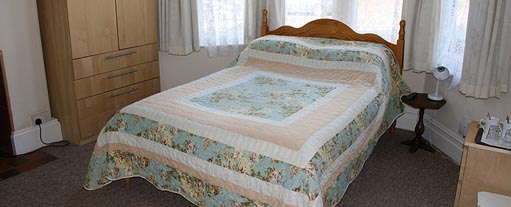 An image of a bedroom containing a double bed and two bedside cabinets along with a wardrobe.