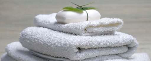 An image of some neatly folded towels with a small bar of soap wrapped in a bow placed on top.